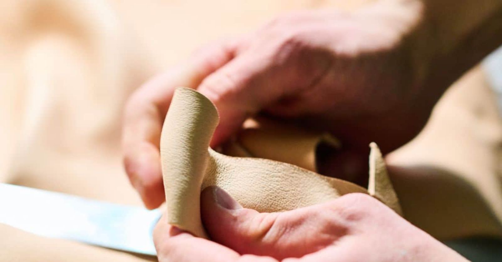 Close-up of Italian artisan handling beige nubuck leather used in MAYADORO dog accessories