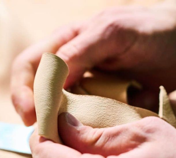 Close-up of Italian artisan handling beige nubuck leather used in MAYADORO dog accessories
